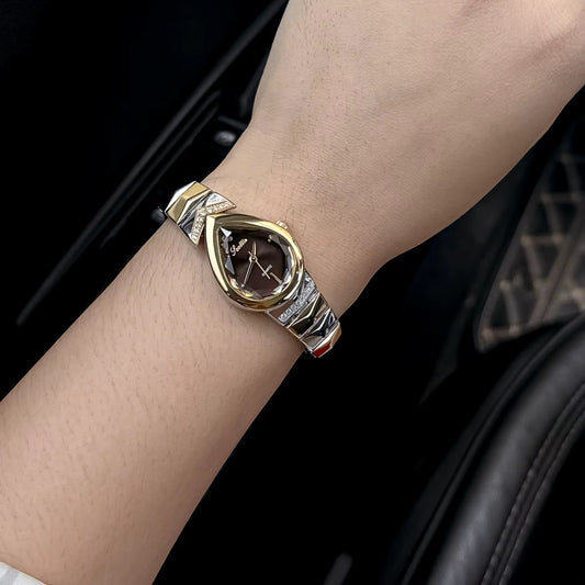 Gold and silver bracelet with a central gemstone on a wrist against a dark background