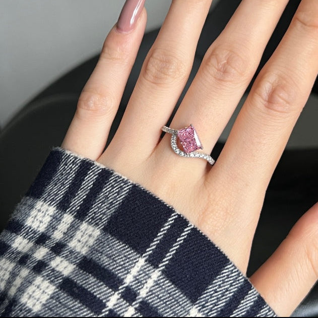Hand wearing a pink gemstone ring with a blurred background